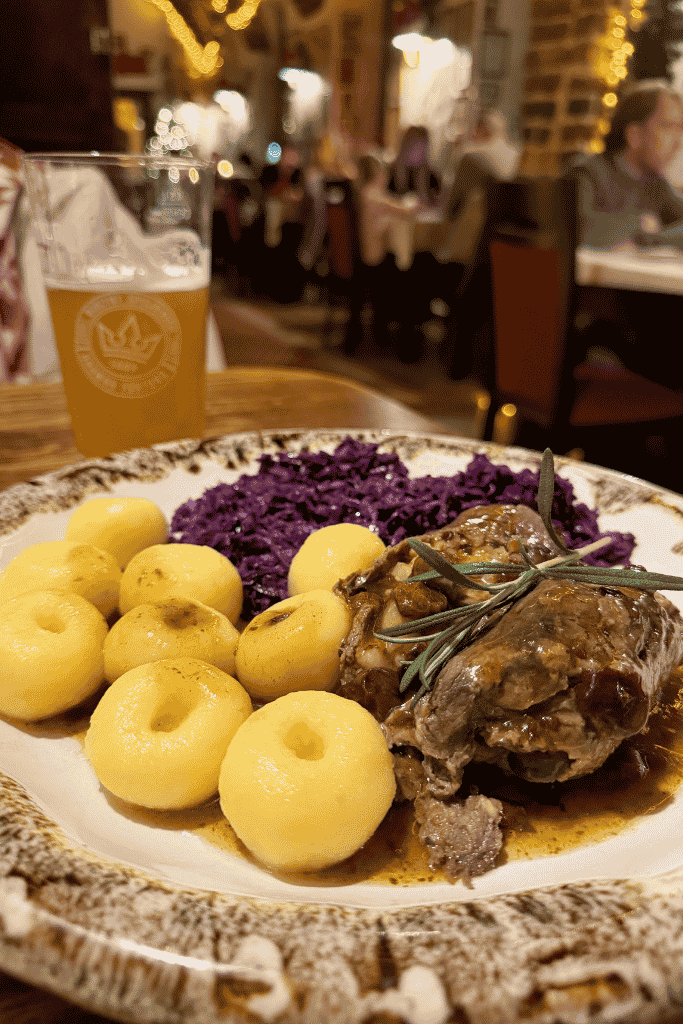 Traditional Polish meal with meat, potato dumplings, red cabbage, and a beer at Konspira restaurant in Wroclaw.