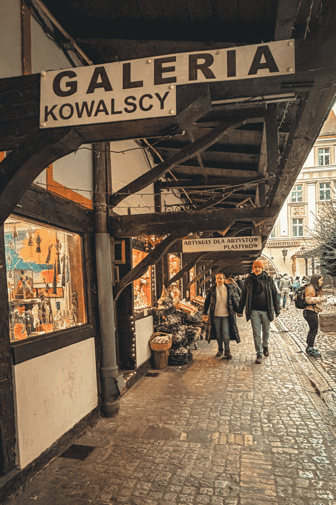 Galeria Kowalscy art gallery and shop stalls along a cobblestone passage in Wroclaw, Poland.