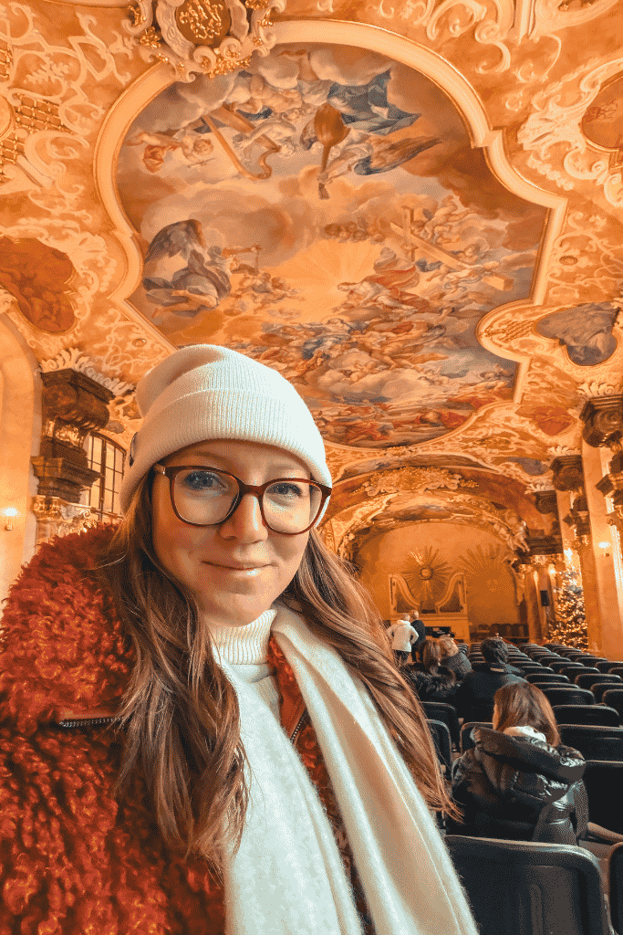 Selfie inside an ornate Baroque-style hall in Wroclaw, Poland, featuring elaborate ceiling frescoes and decorative architecture.