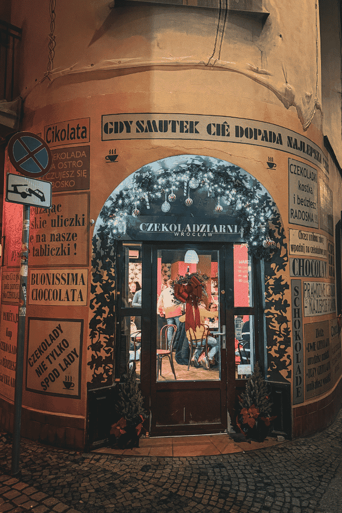 Entrance to Czekoladziarnia Wrocław chocolate café, decorated with festive Christmas garlands and vintage-style chocolate signs.