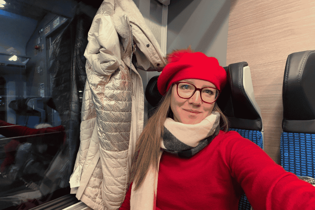 Kate wearing a red beret and winter scarf while traveling by train through Europe.