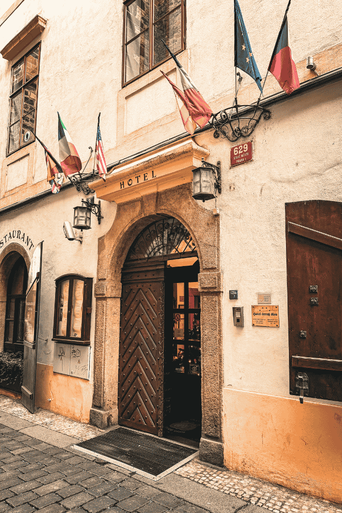 Entrance to Hotel Černý Slon in Prague Old Town, with historic architecture and international flags above the doorway.