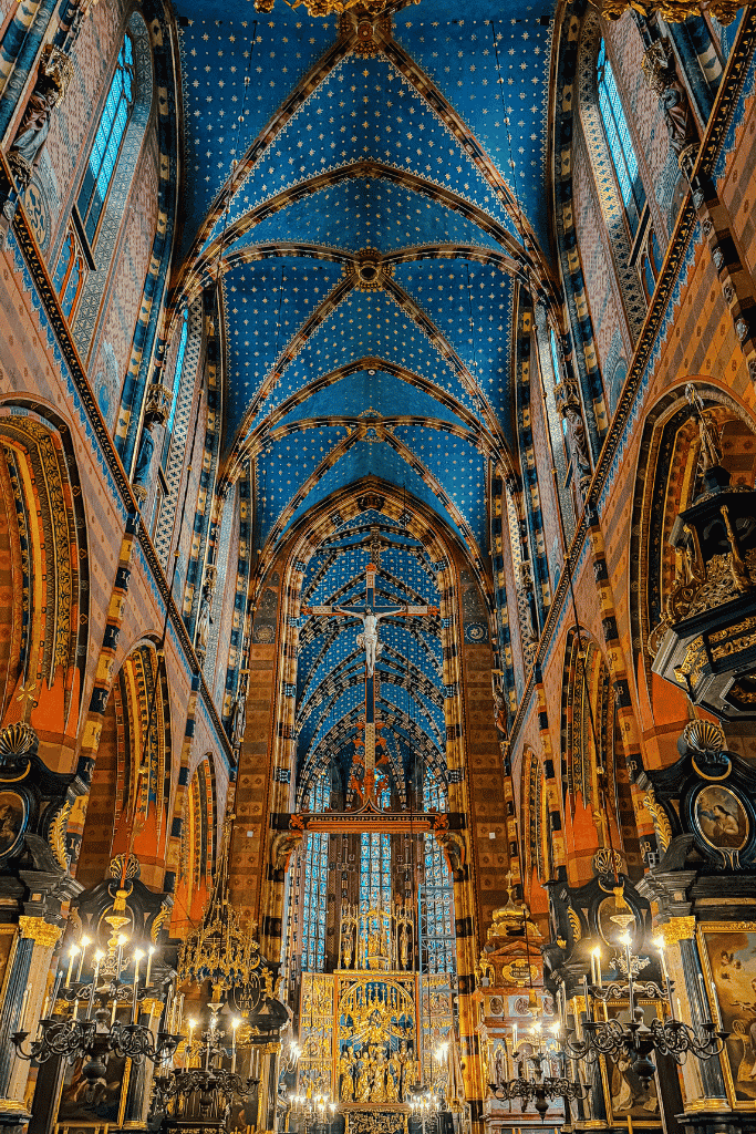 The ornate interior of St. Mary’s Basilica in Krakow, featuring its iconic blue star-covered ceiling and Gothic altar.