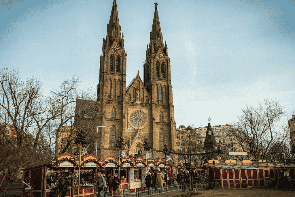 Christmas market stalls in front of the twin-spired Church of St. Ludmila at Náměstí Míru in Prague.