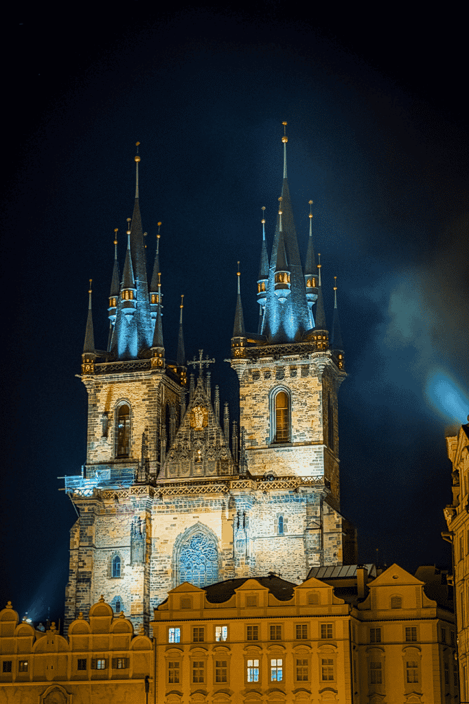 The Church of Our Lady before Týn glowing against the night sky, its dramatic Gothic spires towering over Prague’s Old Town Square.