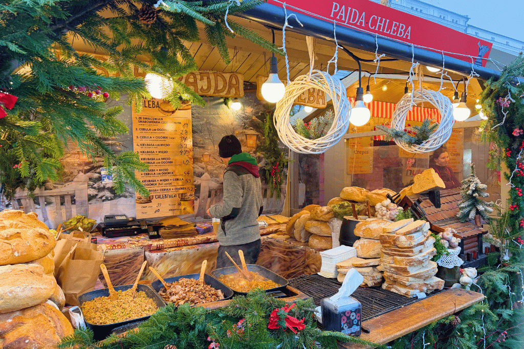 A festive food stall at the Krakow Christmas Market serving traditional Polish dishes, fresh bread, and other local specialties.