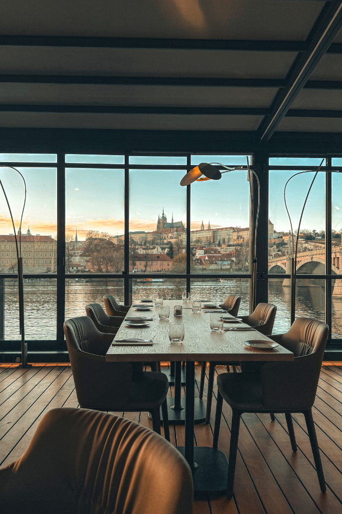 Dinner with a view in Prague, overlooking the Vltava River, Charles Bridge, and the spires of Prague Castle glowing in the distance.