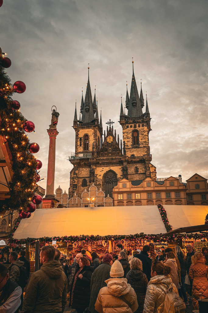 Prague’s Old Town Square Christmas Market comes alive beneath the dramatic Gothic spires of the Church of Our Lady before Týn, with festive stalls and twinkling lights filling the historic square.