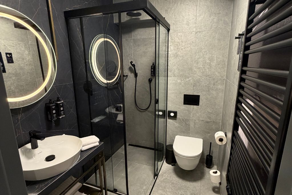 Modern bathroom at Garamond, a Tribute Portfolio Hotel in Krakow with a glass walk-in shower.