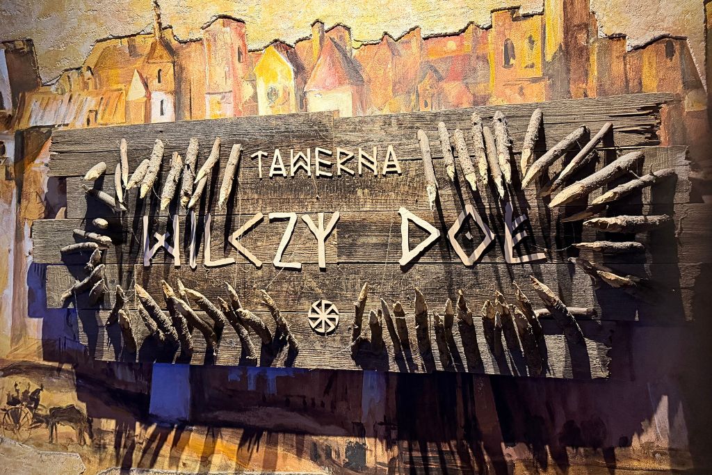 Rustic wooden sign for Tawerna Wilczy Dół restaurant in Krakow.