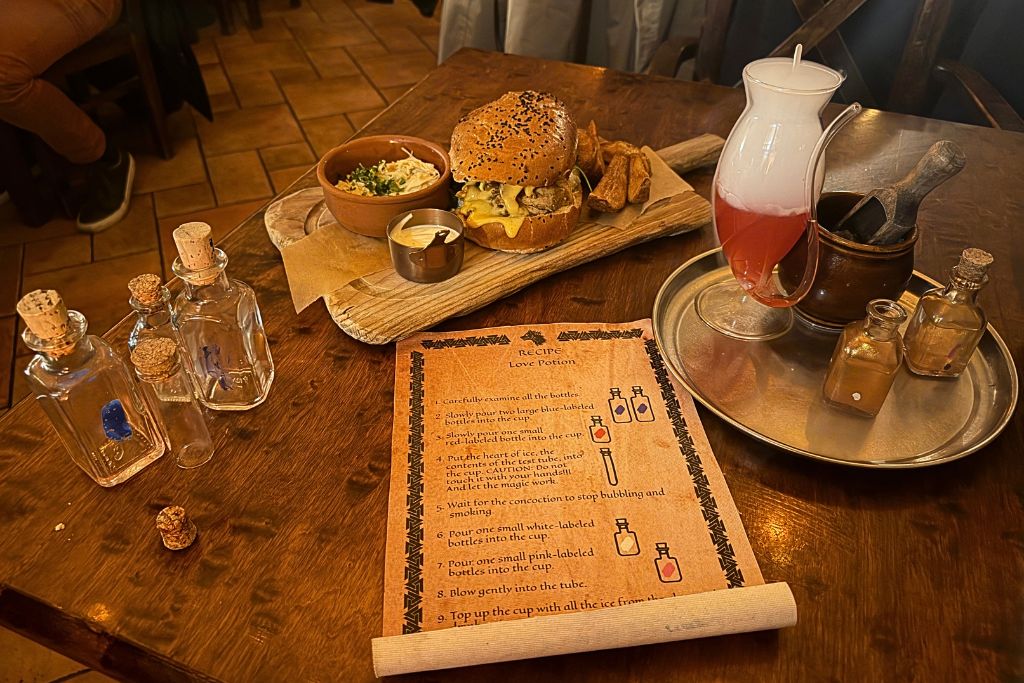 Themed meal with a burger, fries, and interactive love potion drink at Tawerna Wilczy Dół in Krakow.
