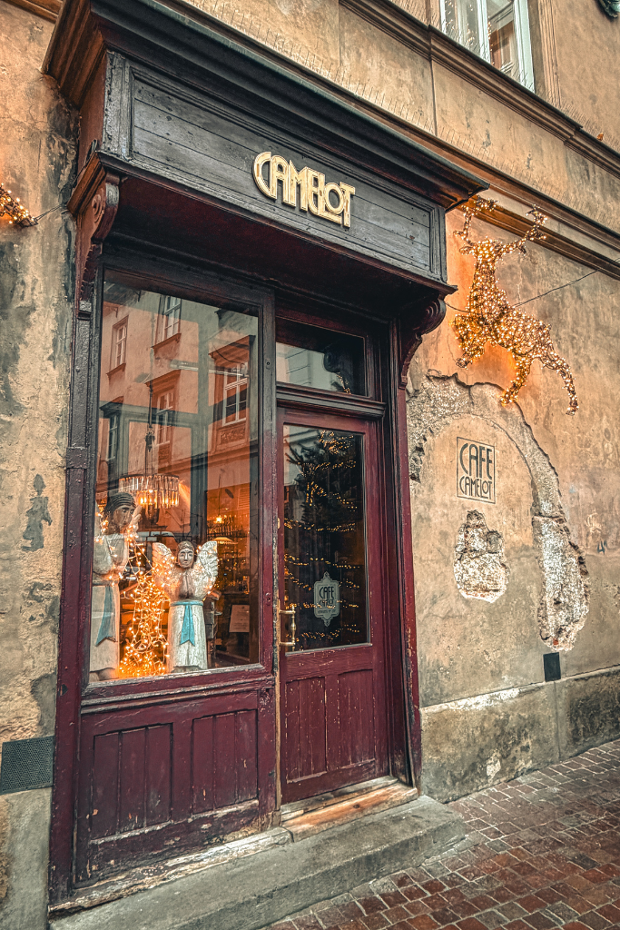 Exterior of Camelot Cafe in Krakow Old Town decorated with festive Christmas lights.