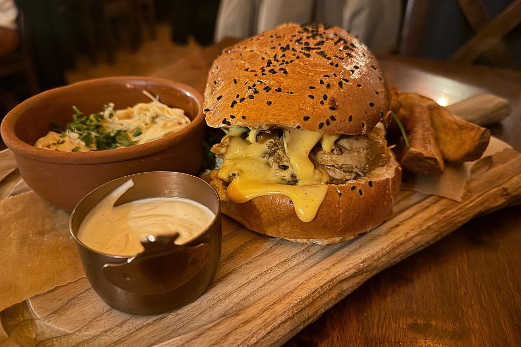 Pulled pork burger with melted cheese, fries, coleslaw, and dipping sauce at Tawerna Wilczy Dół in Krakow.