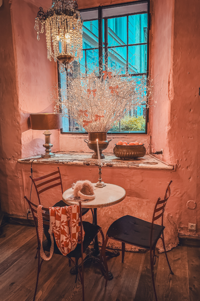 Cozy table inside Camelot Cafe in Krakow decorated with Christmas lights and antique details.