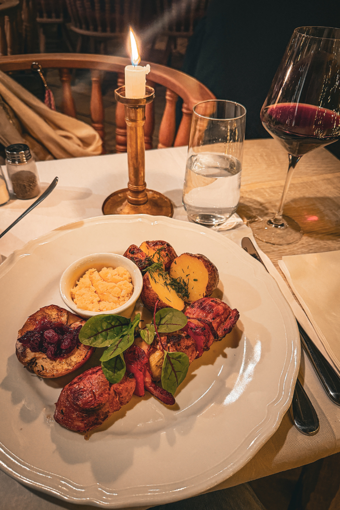 Polish dinner with grilled meat, roasted potatoes, and red wine at Pod Aniołami restaurant in Krakow.
