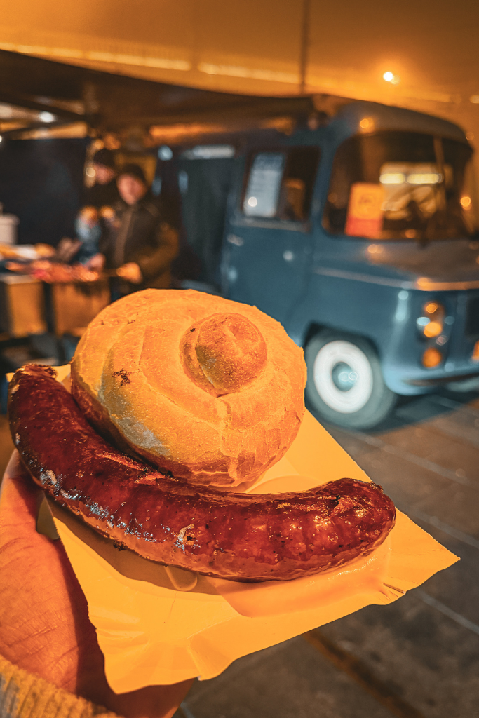 Grilled Polish sausage served with a crusty bread roll at a late-night food stand in Krakow.