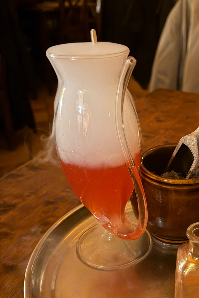 Smoking red Love Potion drink served in a glass pitcher at Tawerna Wilczy Dół in Krakow.