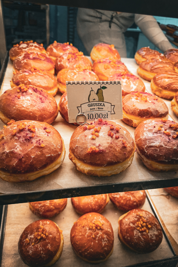 Display of traditional Polish pączki with different fillings at a bakery in Krakow.