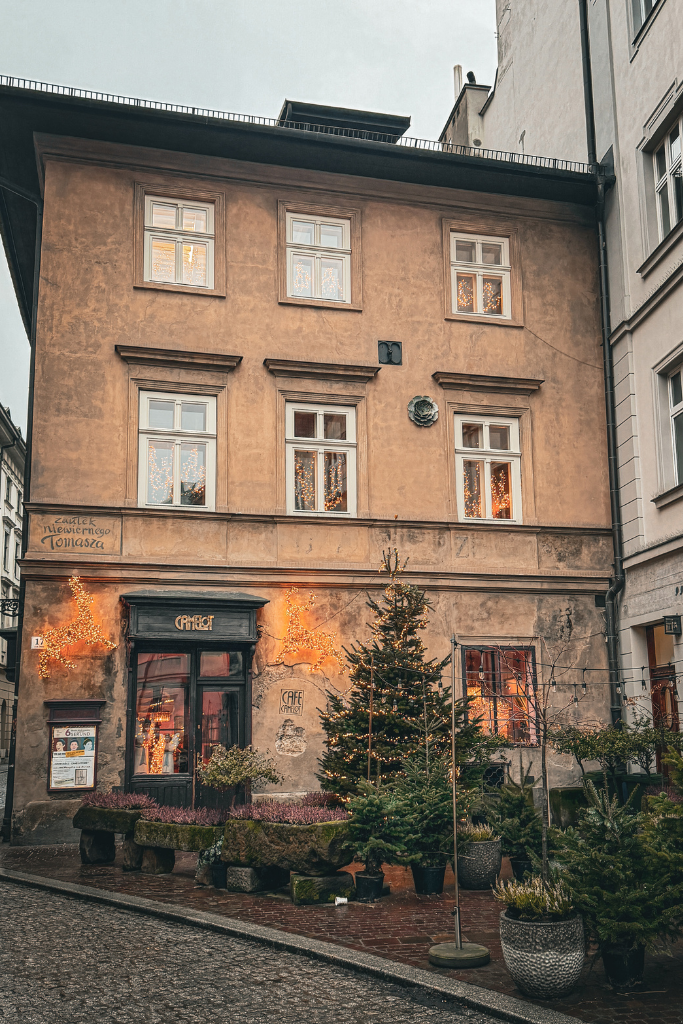Exterior of Camelot Cafe in Krakow decorated with Christmas trees and festive lights.