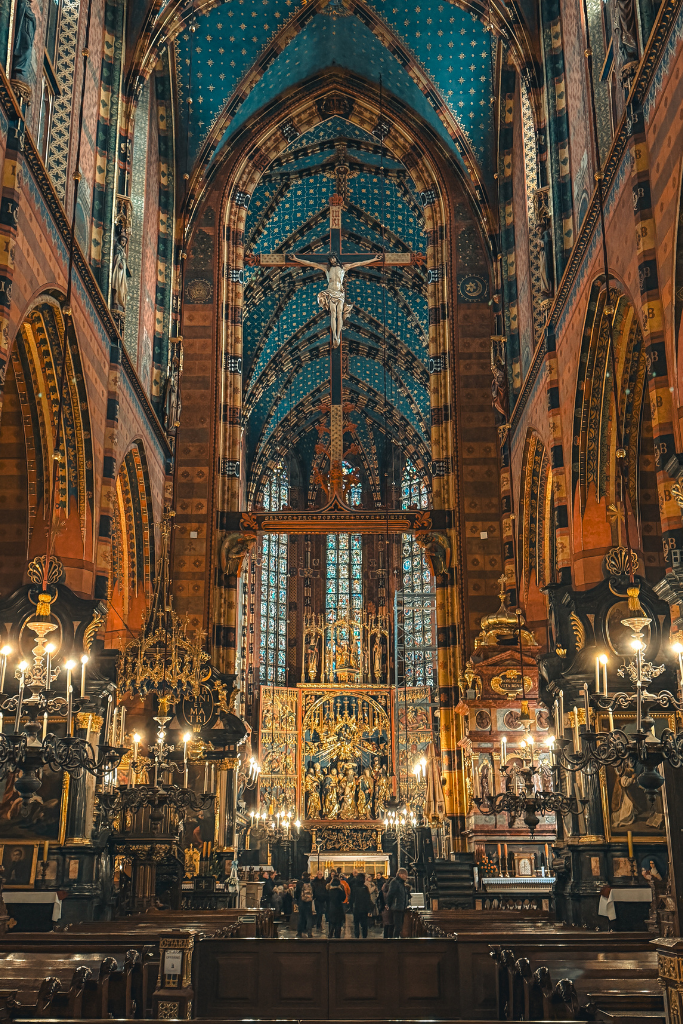 Ornate interior of St. Mary’s Basilica in Krakow, featuring its blue star-covered ceiling, Gothic altar, and hanging crucifix.