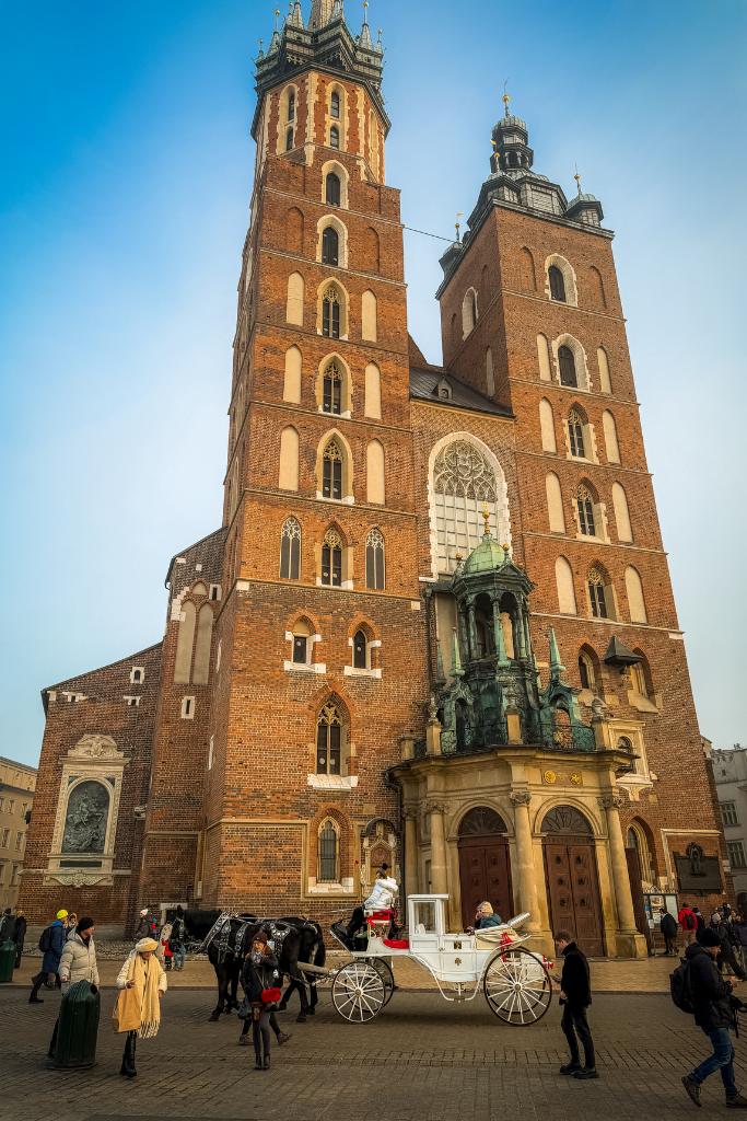St. Mary’s Basilica in Krakow’s Main Market Square with a horse-drawn carriage passing in front of its twin towers.