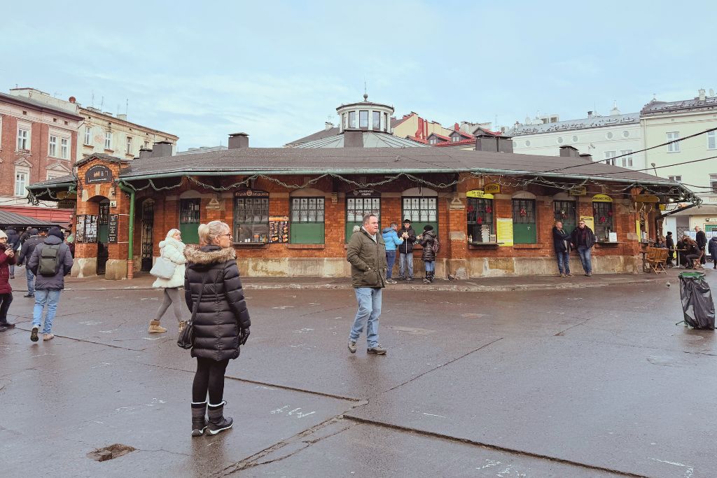 Plac Nowy in Krakow’s Kazimierz district with visitors walking around the historic market square.