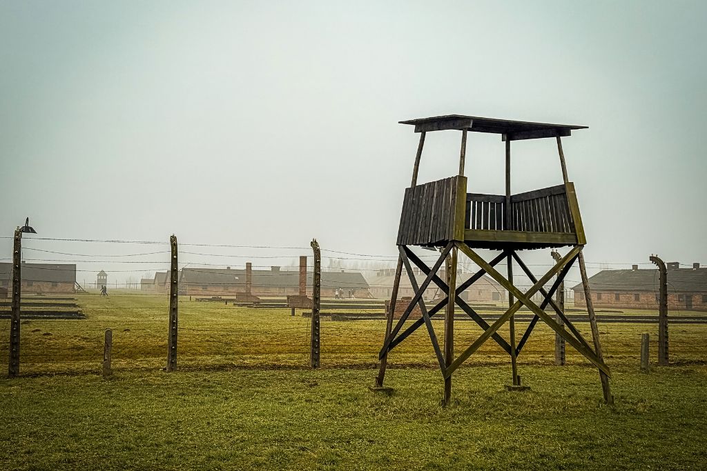 Wooden guard tower and barbed-wire fencing at Auschwitz-Birkenau concentration camp in Poland.