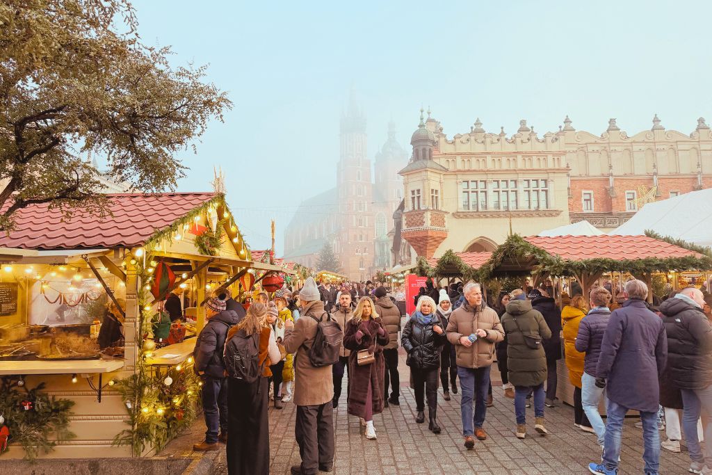 Krakow Christmas Market with festive wooden stalls and crowds in the Main Market Square.
