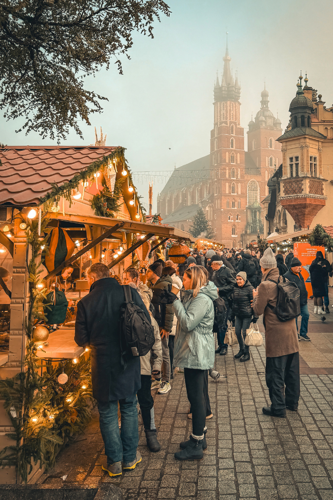 Krakow Christmas Market with festive wooden stalls and St. Mary’s Basilica rising above the Main Market Square.