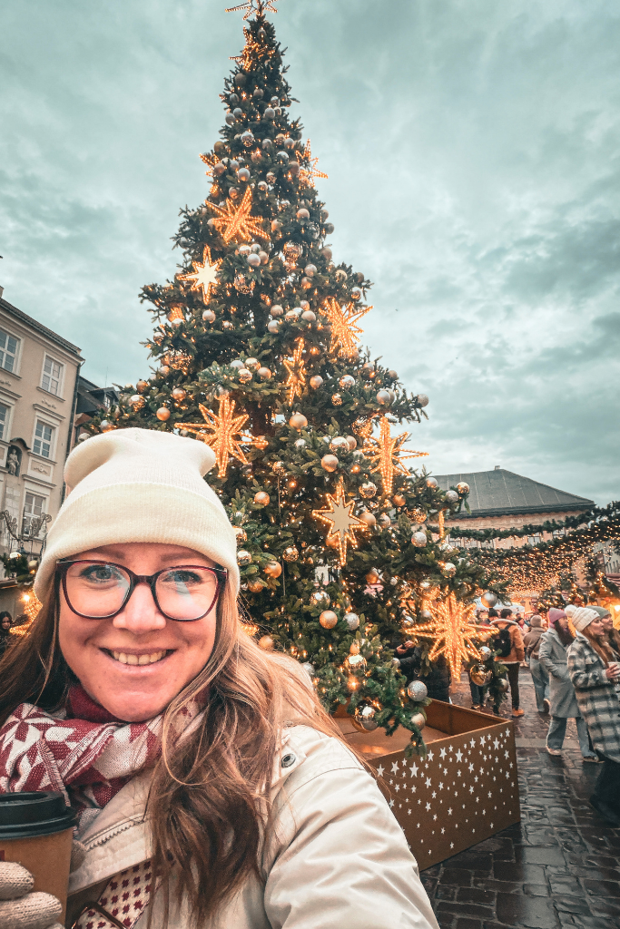 Kate enjoying Krakow’s Little Market Square Christmas Market beside a beautifully decorated Christmas tree.