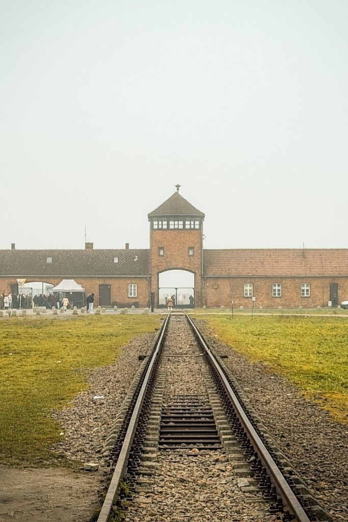 Railway tracks leading through the entrance gate at Auschwitz II-Birkenau Memorial in Poland.