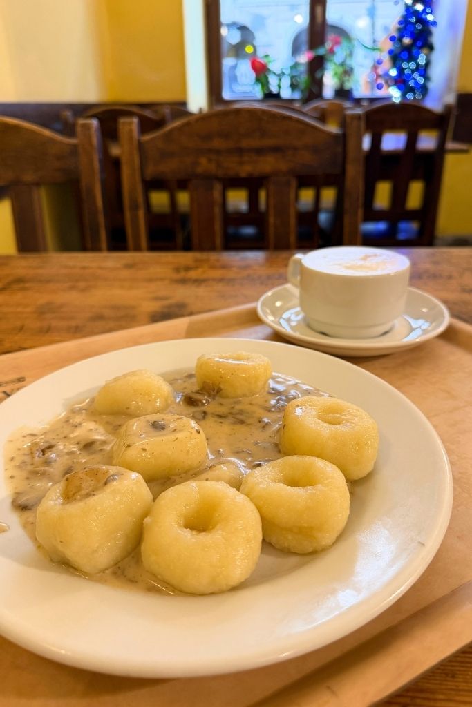 Traditional Polish potato dumplings with creamy mushroom sauce served at a cozy Milk bar in Krakow.