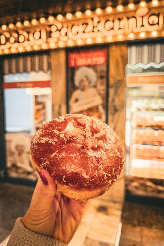 Traditional Polish pączek pastry held outside a bakery in Krakow.
