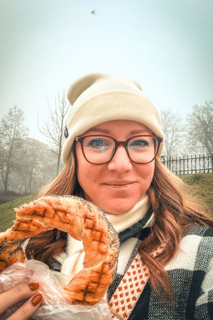 Kate trying a traditional Polish obwarzanek, a ring-shaped bread snack, while exploring Krakow