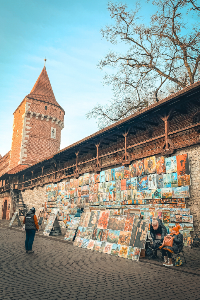 Local artists selling colorful paintings along the historic Krakow city walls near St. Florian’s Gate.
