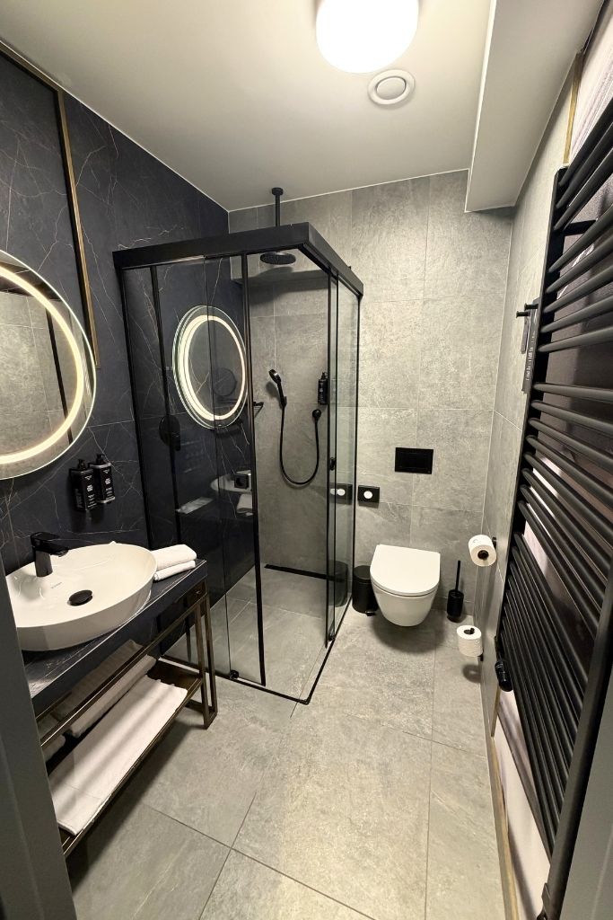 Modern bathroom at Garamond, a Tribute Portfolio Hotel in Krakow with a glass walk-in shower.