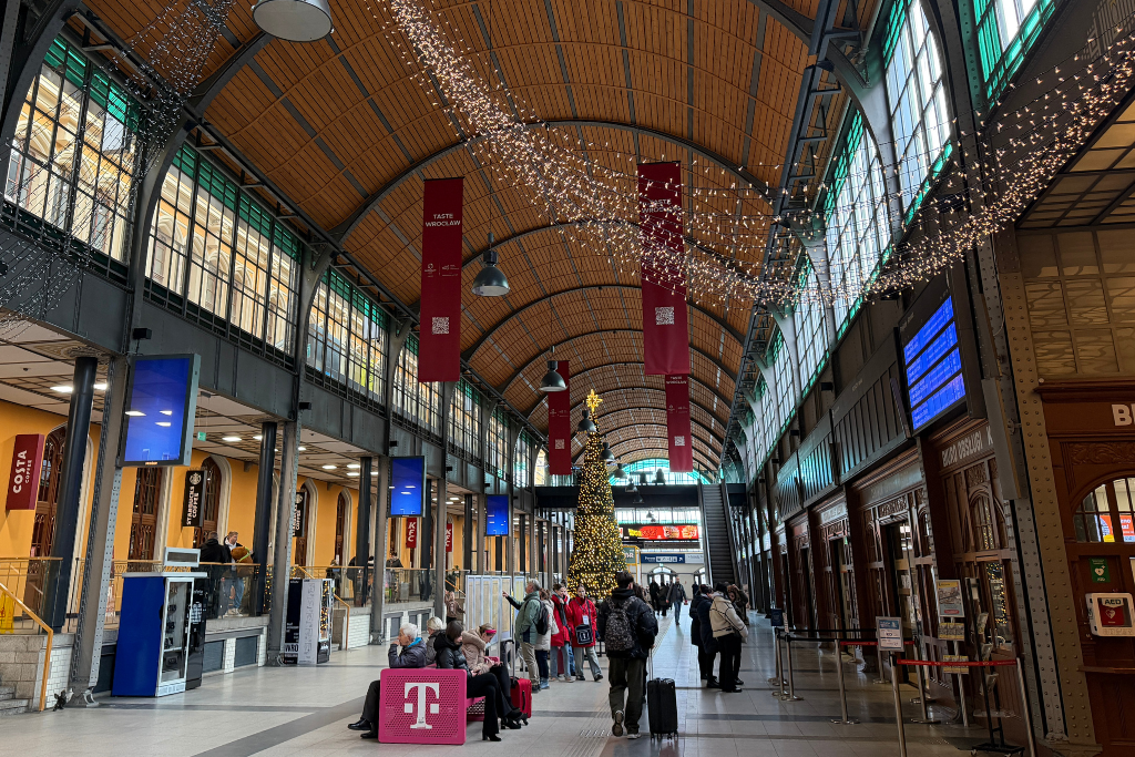 Interior of Wroclaw Glowny train station decorated with Christmas lights and a Christmas tree.