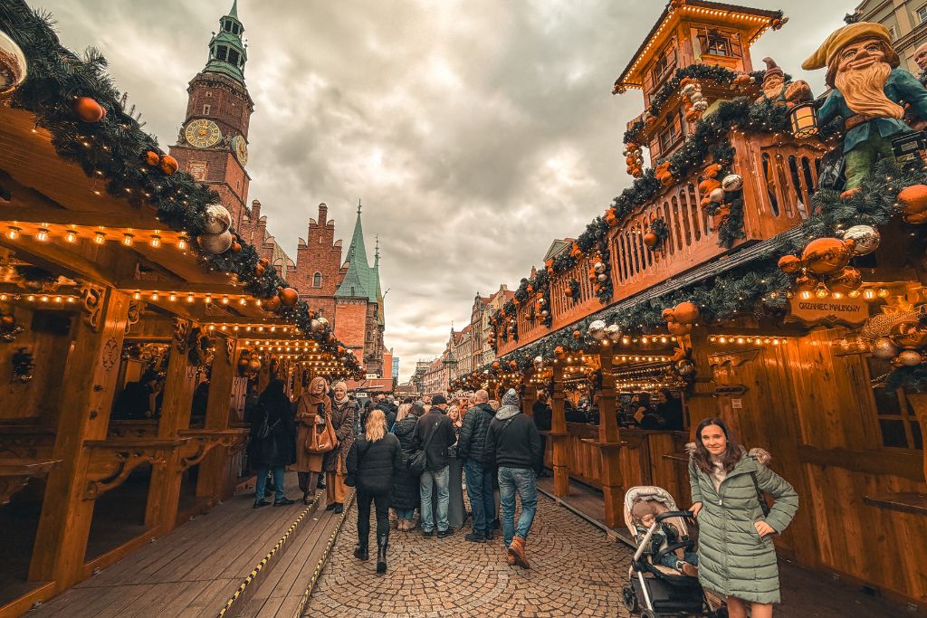 Festive wooden stalls packed with visitors at Wroclaw Christmas Market beside the historic Old Town Hall.