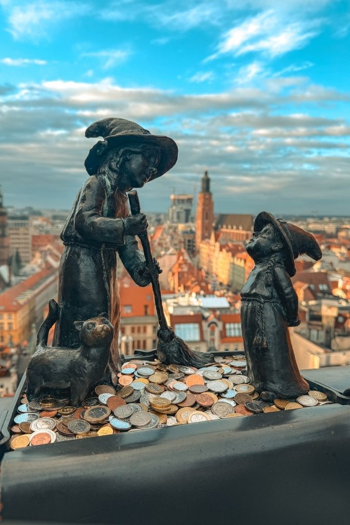 Wroclaw dwarf statues surrounded by coins on the Bridge of Penitents, overlooking Wroclaw Old Town.