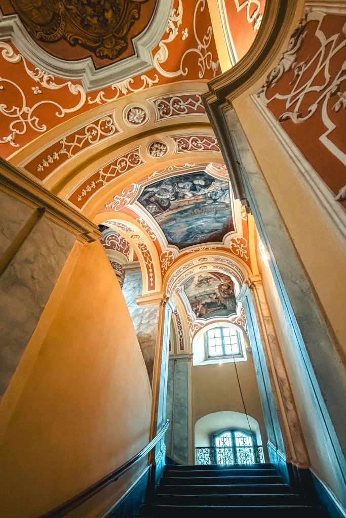 Decorative staircase inside the University of Wroclaw featuring colorful Baroque frescoes, ornate arches, and historic architectural details.