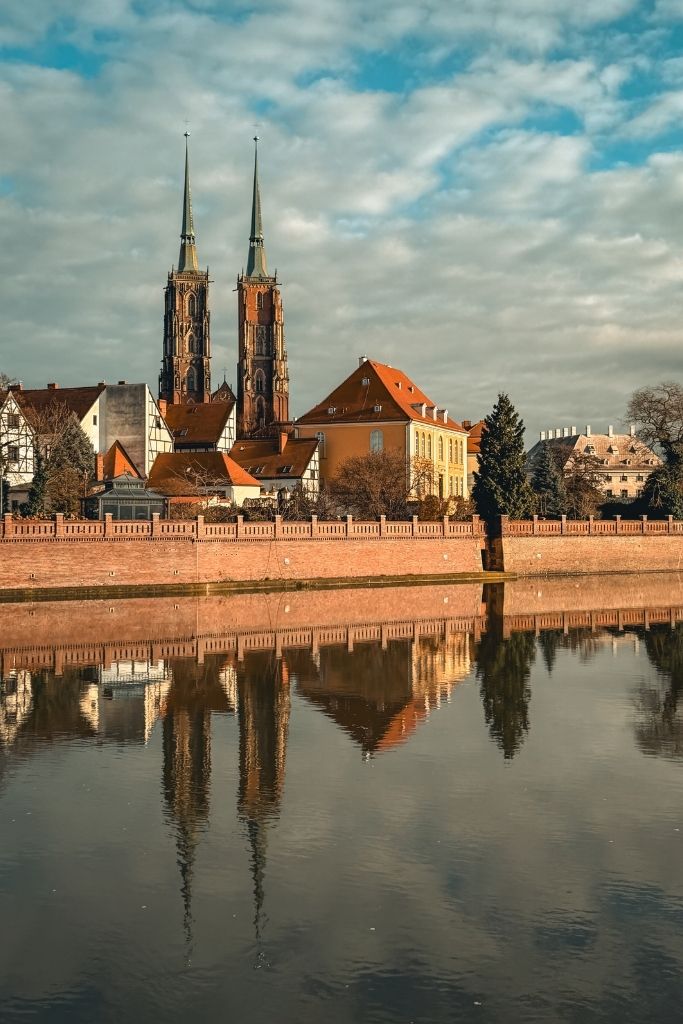 Wroclaw Cathedral and historic Cathedral Island reflected in the calm waters of the Oder River.