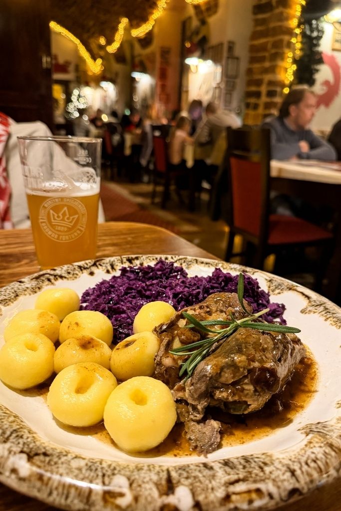 Traditional Polish meal with meat, potato dumplings, and red cabbage served inside Konspira restaurant in Wroclaw.