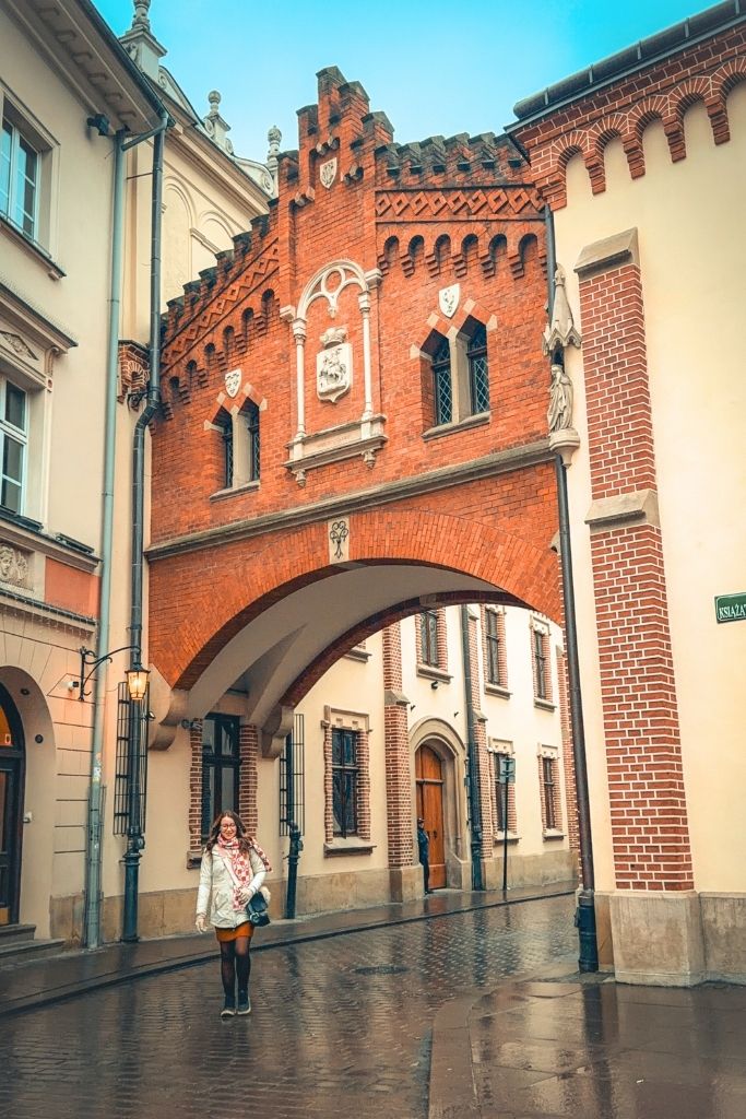 Wandering Krakow’s historic streets beneath a red-brick archway.