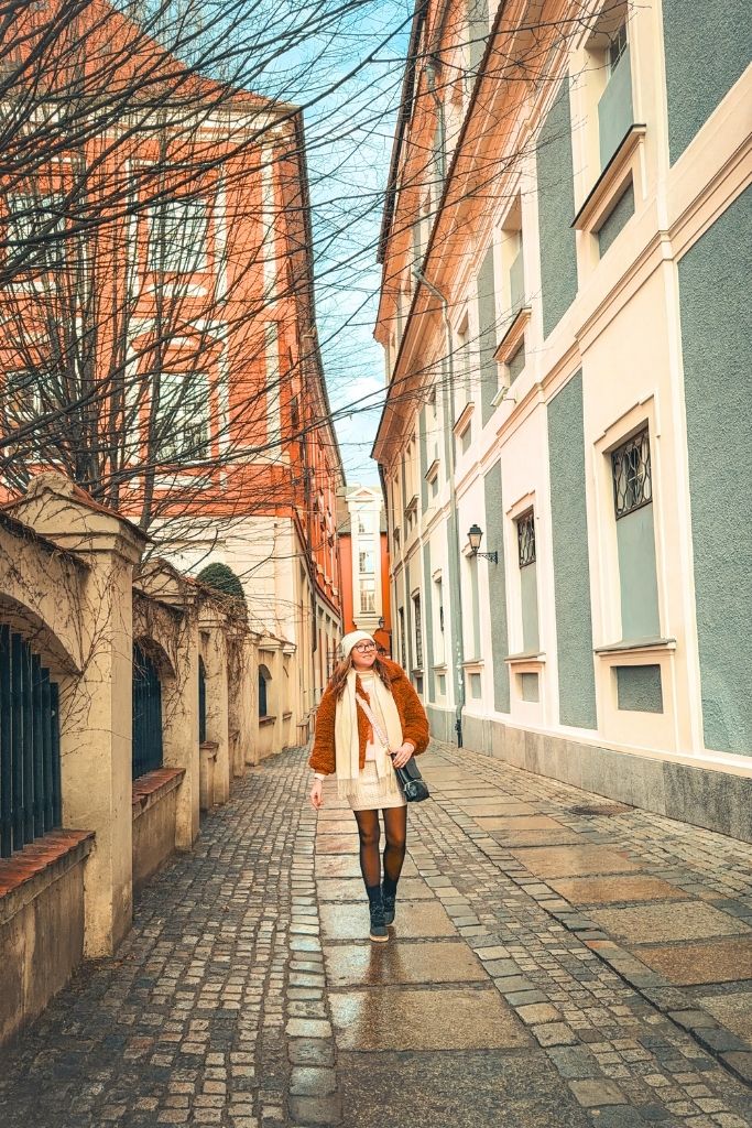 Exploring a quiet cobblestone street in Wroclaw lined with pink and blue buildings.